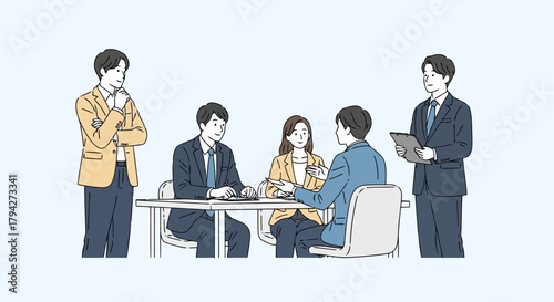 A group of people in a meeting, with two men standing and observing the others seated around a table