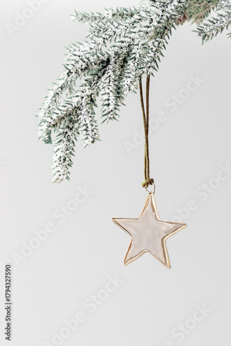 Christmas bauble shiny golden star hanging on green Christmas fir branch. Festive holiday chrome metallic decoration, minimal style. Xmas greeting cards, new year aesthetic background, copyspace