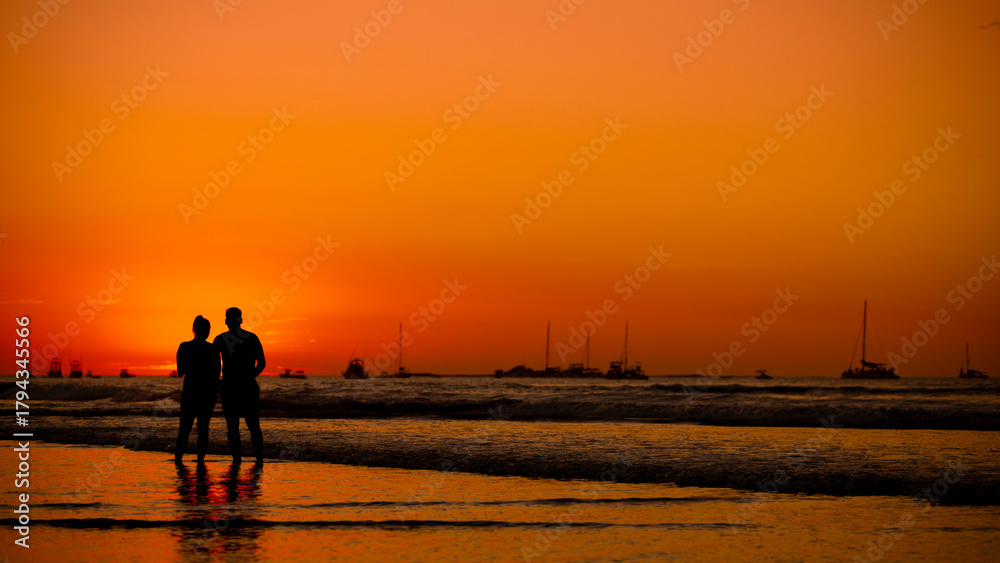 Fototapeta premium Silhouette of a couple looking at sunset on a tropical beach