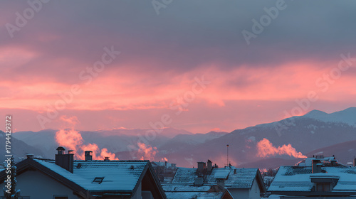 Rooftops covered in snow with smoke rising against a pink and purple sky at dawn or dusk