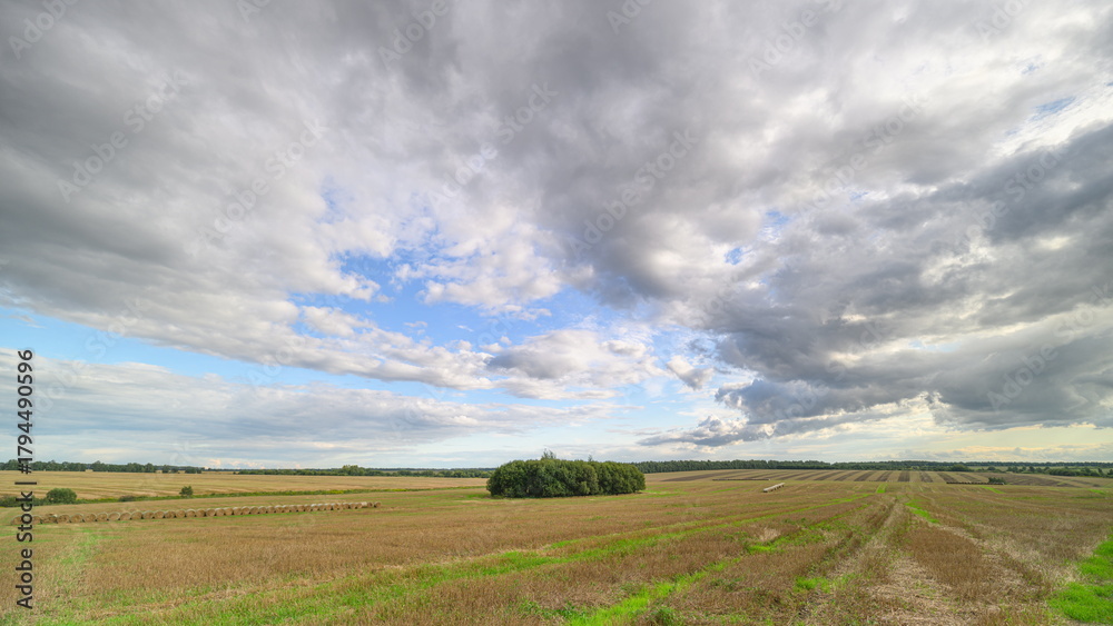 Fototapeta premium An Expansive Agricultural Landscape With Bountiful Fields Under a Dramatic Cloudy Sky