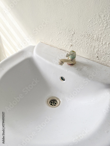 Broken Washbasin on Damped, Musty Old Painted Wall with Sunlight and Striped Shadow. Textured Exterior Toilet Wall in Room at Dhamma Retreat Center, Saraburi, Thailand. 25 OCT 2025. A.M.