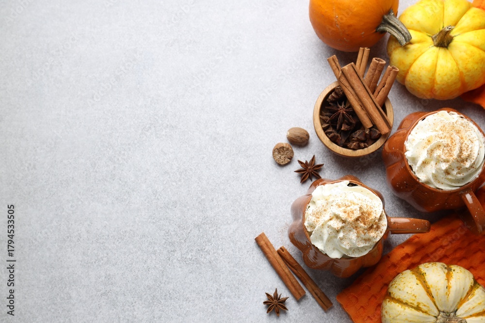 Obraz premium Tasty pumpkin latte with whipped cream in cups, spices and ingredients on light grey table, flat lay. Space for text