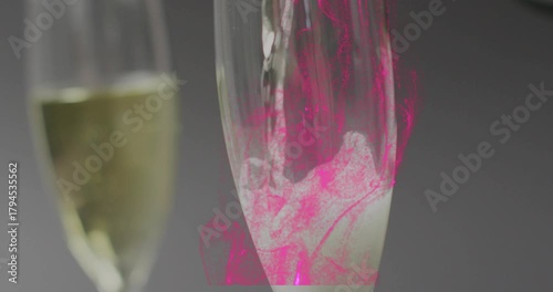 Pink droplet falling from top starting bottle pouring, tall flute filling and making frothy swirls