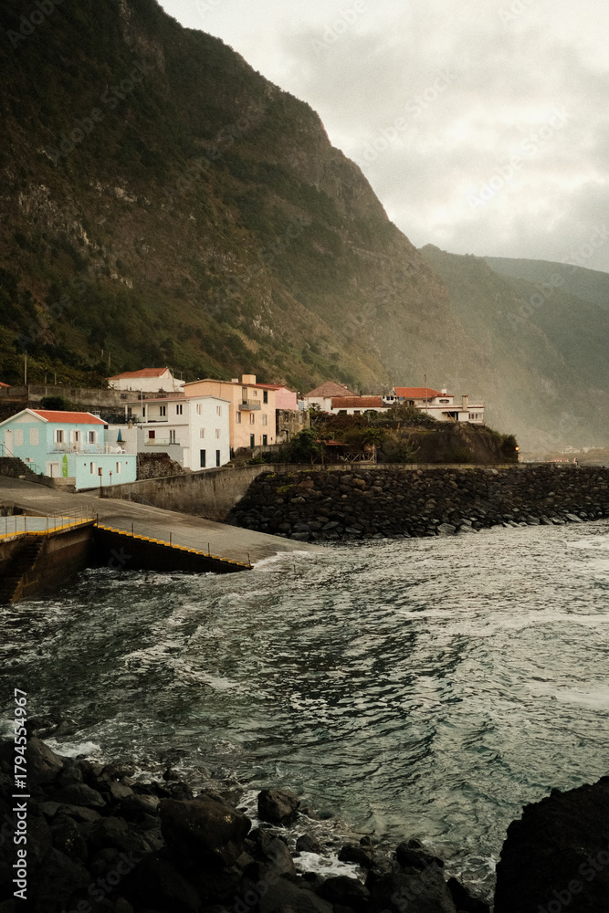 Fototapeta premium Rugged shoreline settlement under dynamic sky with rocky