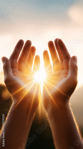 Two raised hands capture warm sunlight shining through in a serene outdoor setting.
