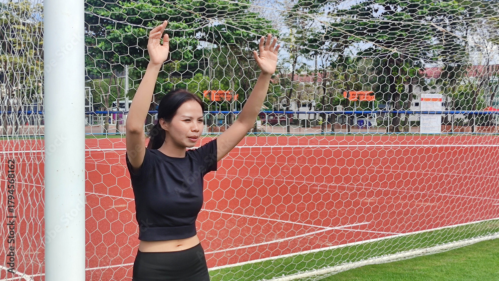 Obraz premium Soccer Goal Keeper in Action: A determined soccer goal keeper stands confidently in front of the goal, her arms raised in anticipation. The image captures the focus, athleticism.