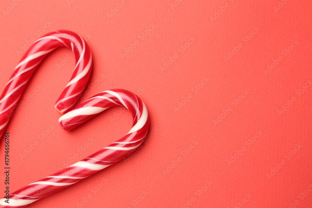 Naklejka premium Heart made of tasty candy canes on red background, flat lay with space for text. Merry Christmas and Happy New Year