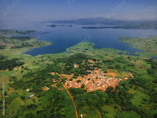 Aerial view of a tapestry of green foliage meets the tranquil blue waters of a vast lake, Tepo, Oti Region, Ghana.
