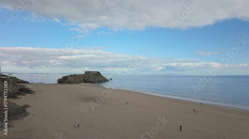 Tenby south beach at low tide with St Catherines Island in the distance on a bright sunny day.
