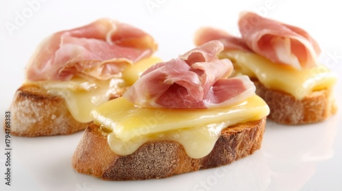 Freshly toasted slices of bread showcase a generous layer of creamy cheese, topped with savory slices of ham. Ideal for a light meal or snack, this dish brings comfort and flavor together