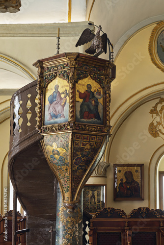  Elevated church pulpit with ornate gold decorations and painted panels depicting saints or biblical scenes, in The Panagia Tourliani monastery in Mykonos 