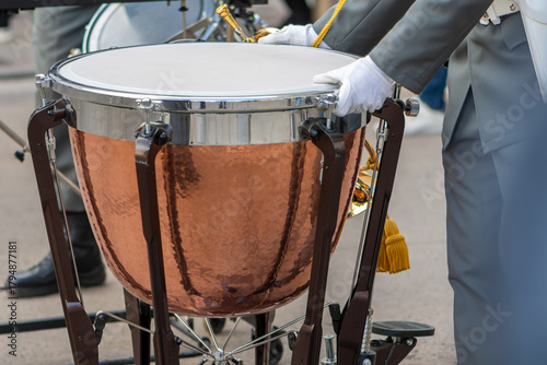 A large timpani with a shiny copper surface is placed in front of the musician.