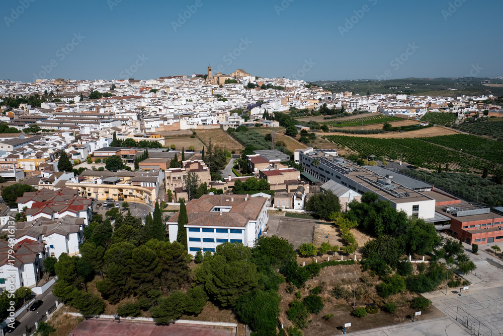 Fototapeta premium Drone view of Montilla town with its mix of traditional white buildings, modern architecture, and surrounding farmland in the heart of Andalusia, Spain.