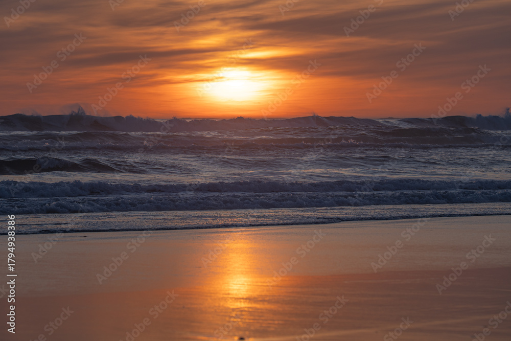 Fototapeta premium Atlantic sunset with rough waves and golden reflection on sandy beach
