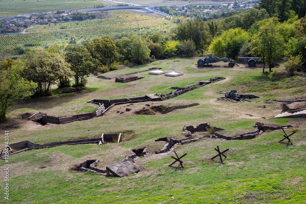 Obraz premium Trenches, dugouts, guns on a hillside on a clear sunny day. Military equipment of the Second World War.