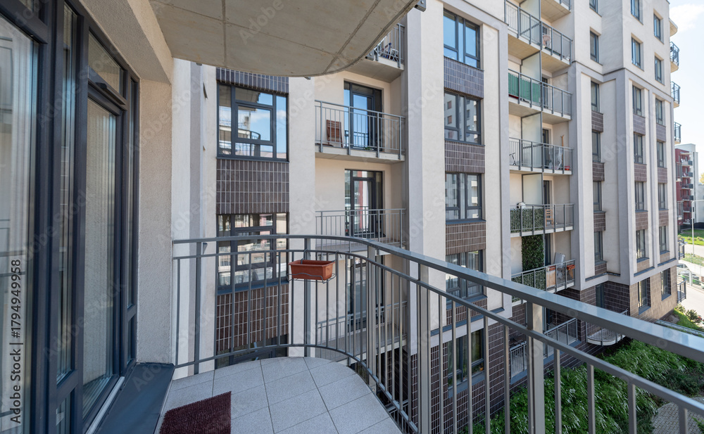 Naklejka premium Modern Apartment Balcony Overlooking Urban Courtyard with Contemporary Architecture