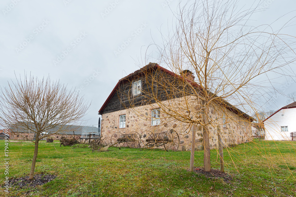 Fototapeta premium Nurme Manor Building with Antique Agricultural Tools on the Lawn