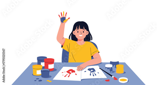 A young girl happily shows off her painted hand after creating colorful handprints on paper.