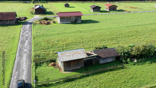Rural landscape with barns and farm buildings surrounded by green fields and a winding country road
