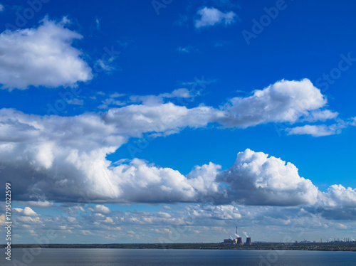 Industrial power plant by lake under blue sky