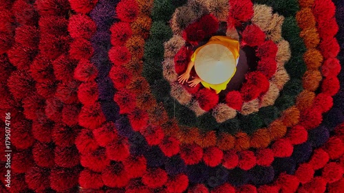 Aerial view of colorful concentric circles of incense sticks with a woman wearing a traditional hat, inciense town, Hanoi, Vietnam.