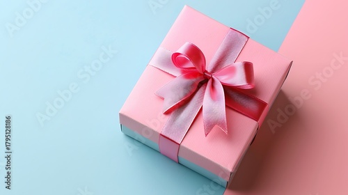 Close up of a pink gift box with a pink ribbon on a blue and pink background in a studio setting
