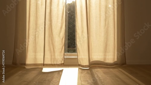 Sheer Curtains Gently Billow in a Breeze as Morning Sunlight Casts Shadows on a Wooden Floor.
