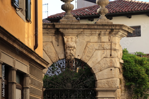 Entrance Gate Detail with Sculpted White Frame and Black Iron Grill in Cividale del Friuli, Italy