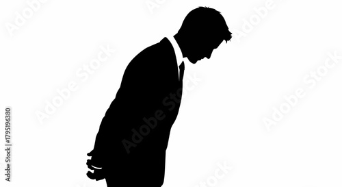 Silhouette of a man in a suit bowing his head in contemplation.