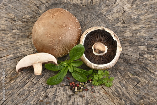 Fresh mushrooms - champignons, with parsley and pepper on a wooden background.