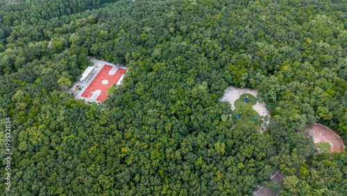 Aerial drone view of entertainment area with basket ball court and kids playground surrounded by green tropical vegetation on a sunny day in Playa del carmen 