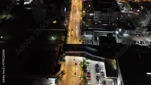 Dynamic night city view taken from above, showing bright city lights and traffic on the streets.