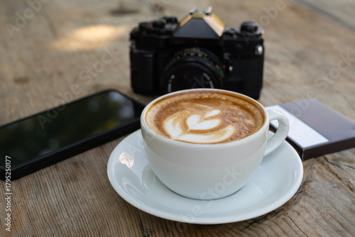 Creative workspace with coffee, camera, and phone. Latte coffee with camera and smartphone on wooden table. Coffee break with camera and mobile phone.