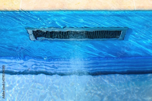 Close-up of a pool skimmer integrated into the side wall, with water actively circulating through it. The skimmer is part of the pool’s filtration system, helping to maintain water clarity