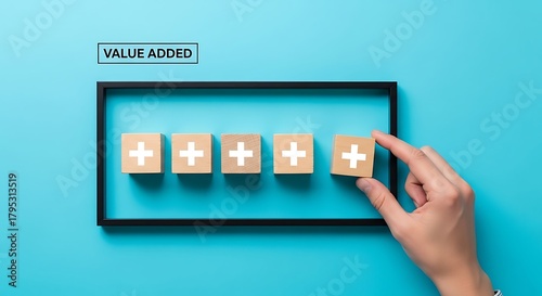 Hand adding value added wooden block in a frame on a blue background