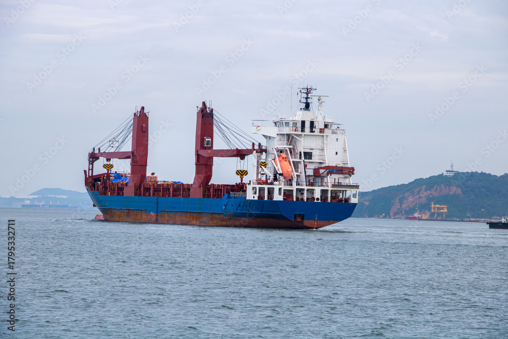 Fototapeta premium Large General Cargo Vessel with Cranes Moving Through Seascape,Cargo Ship Sailing on the Ocean