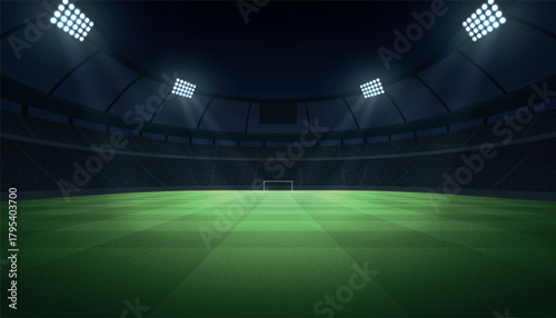 Modern football stadium illuminated by floodlights, showing green pitch and empty goalpost.