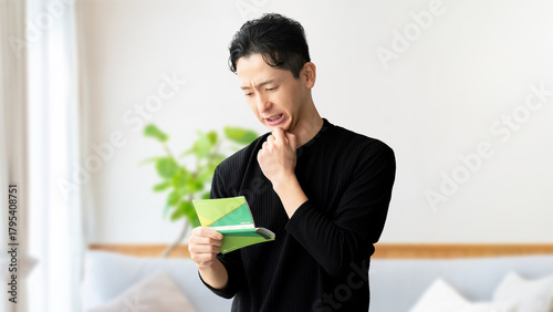 Photos 通帳を見て考える男性