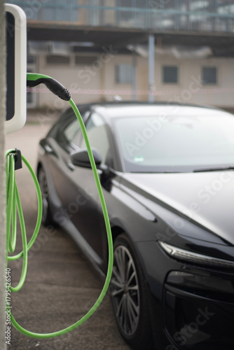 Elektroauto an Ladestation mit grünem Ladekabel im urbanen Umfeld
