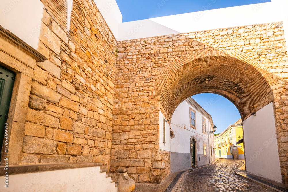 Obraz premium Arco do Repouso, a historic archway in Faro, Algarve, Portugal, showcasing traditional stone architecture