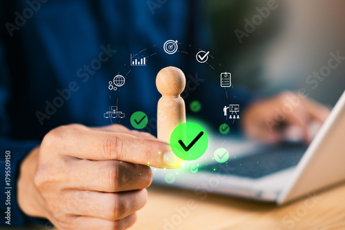 Hand holding wooden figure with digital icons and check marks, symbolizing talent approval, HR evaluation, employee selection, business management