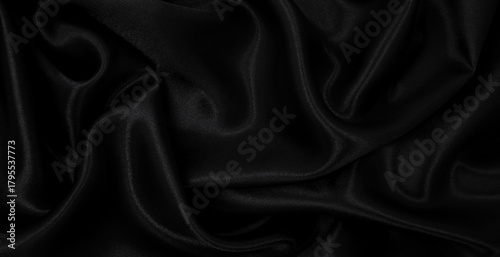 Smooth elegant black silk or satin luxury cloth texture as abstract background. Luxurious background design