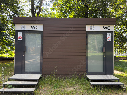 Public space in park with modern restroom for men and women. New restrooms are being installed in city parks to provide comfortable environment. Outdoor urination and gender specific signs