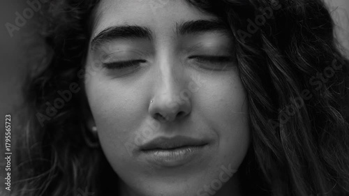 Portrait of young woman with subtle and introspective expression, direct gaze suggesting quiet strength and self-awareness, in black and white
