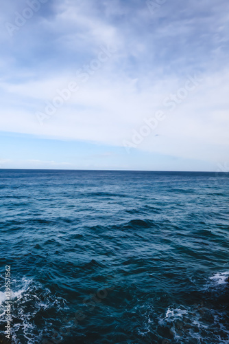 Paisaje del mar azul intenso con horizonte y cielo azul claro con nubes 