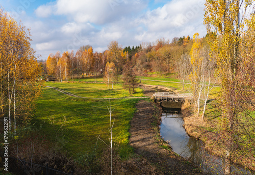 autumn landscape with a wooden bridge over a small river
