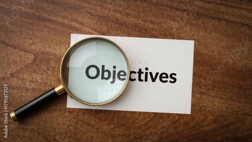 Object objectives written on paper with magnifying glass on wooden surface.