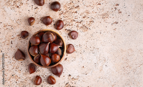 Fresh chestnuts displayed in a wooden bowl and on beige background with copy space, banner simple and clean composition