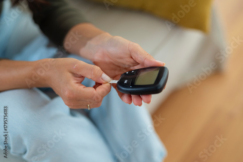 Close-up of a woman inserting a test strip into a glucose meter to measure blood sugar levels.
